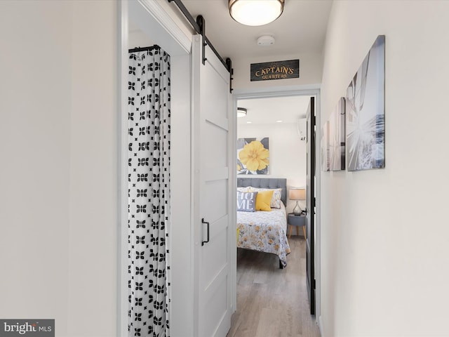 corridor featuring a barn door and light hardwood / wood-style floors