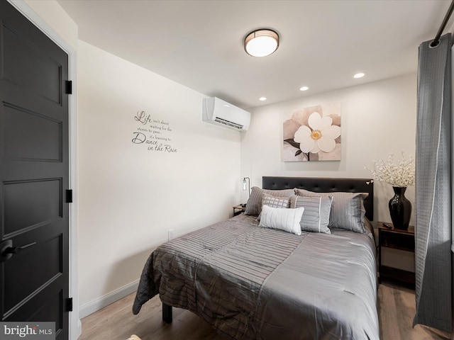 bedroom with light hardwood / wood-style floors and an AC wall unit