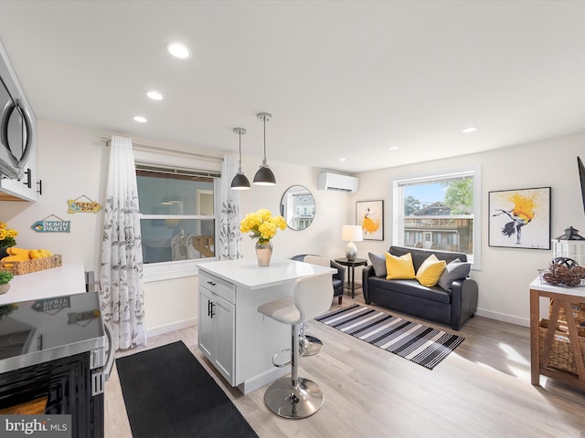 kitchen featuring a wall mounted AC, a kitchen bar, pendant lighting, light hardwood / wood-style flooring, and a center island