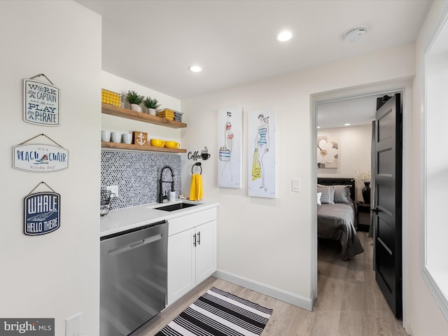 bar featuring white cabinets, light hardwood / wood-style floors, sink, decorative backsplash, and stainless steel dishwasher