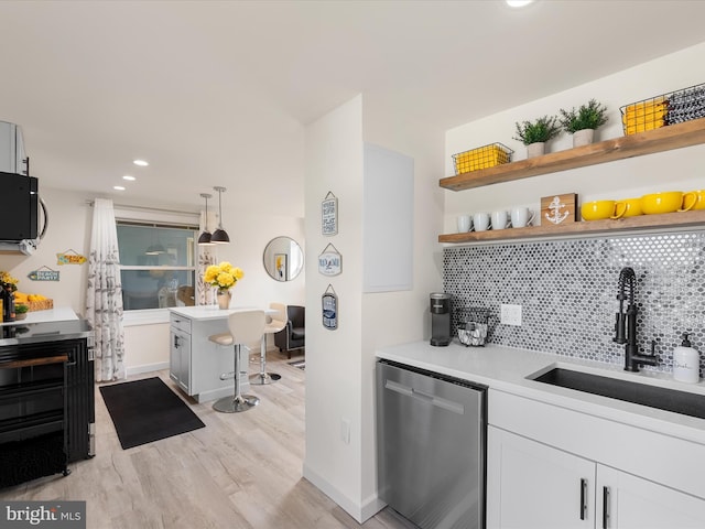 kitchen featuring a kitchen bar, appliances with stainless steel finishes, decorative light fixtures, white cabinets, and sink