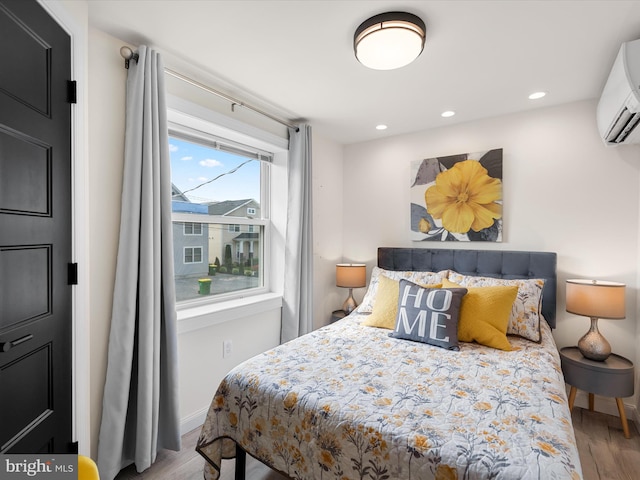 bedroom with a wall mounted AC and hardwood / wood-style flooring