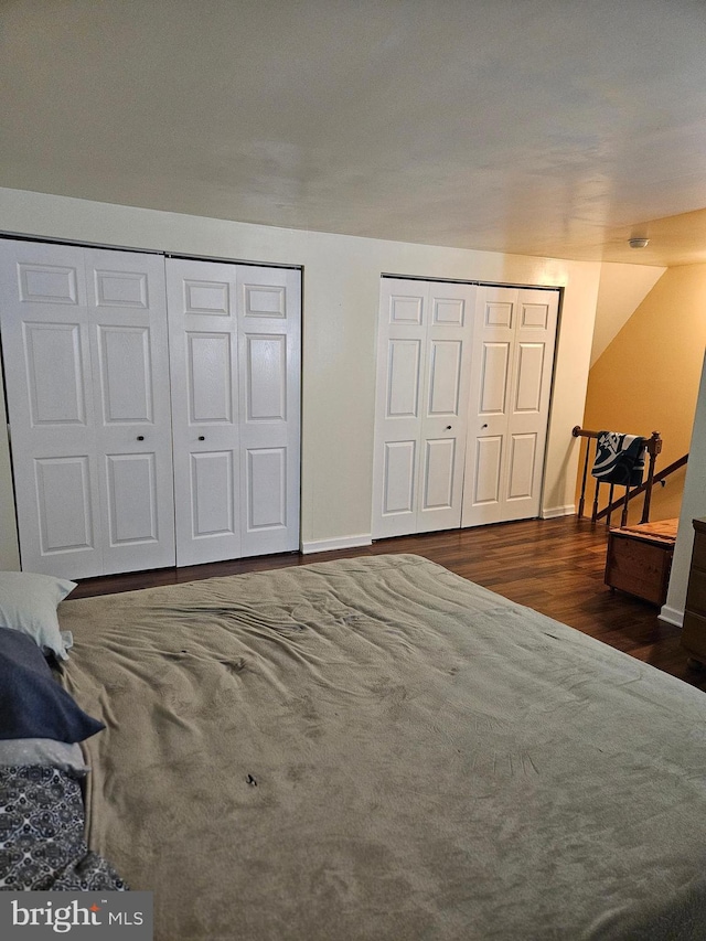 bedroom featuring two closets and dark hardwood / wood-style floors