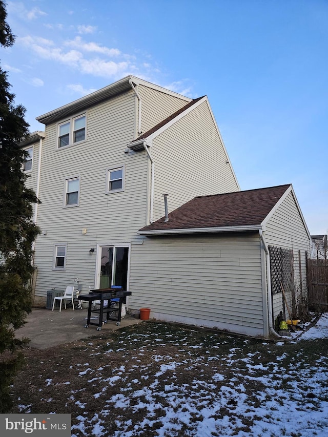 snow covered rear of property featuring central AC unit and a patio area