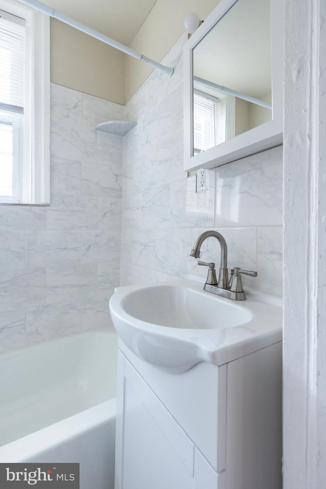 bathroom featuring vanity, decorative backsplash, tile walls, and tiled shower / bath combo