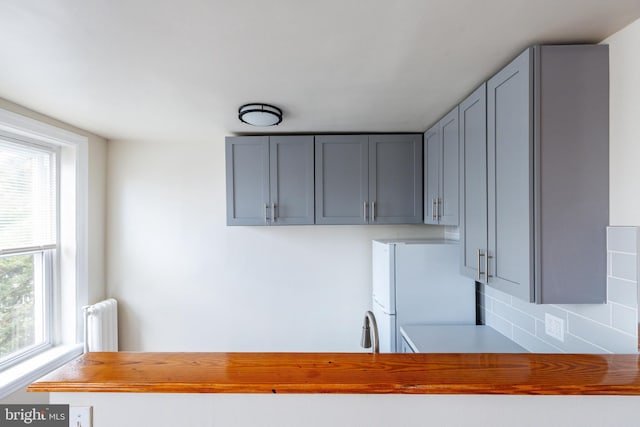 kitchen featuring radiator, gray cabinets, and white refrigerator