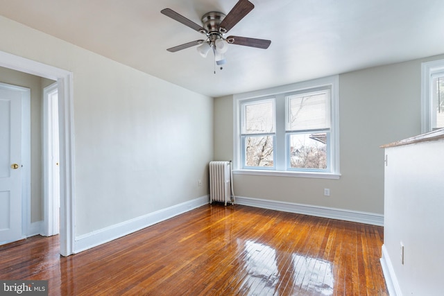 spare room with dark wood-type flooring, radiator heating unit, and ceiling fan