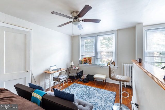 sitting room featuring dark wood-type flooring, ceiling fan, and radiator