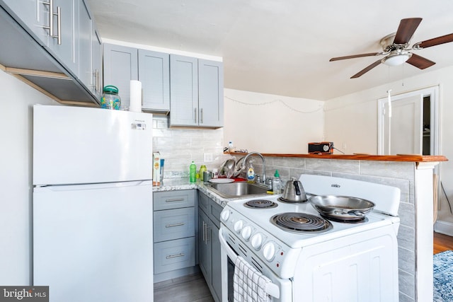 kitchen featuring sink, white appliances, gray cabinets, hardwood / wood-style flooring, and tasteful backsplash