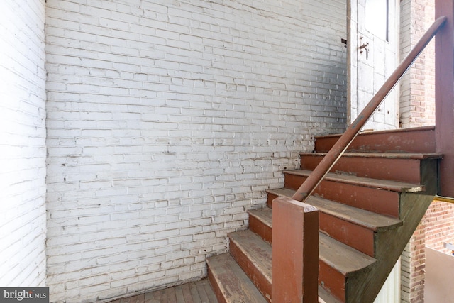 stairway featuring brick wall