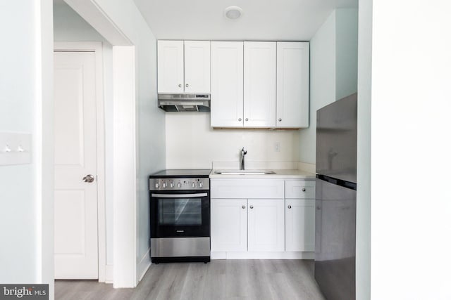 kitchen with appliances with stainless steel finishes, sink, white cabinets, and light hardwood / wood-style floors