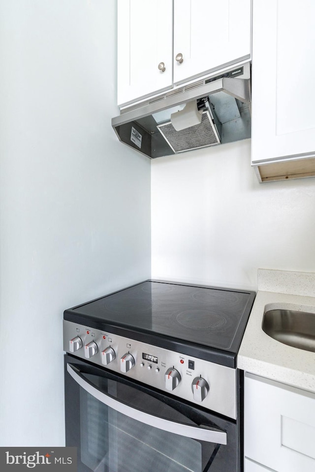 kitchen with stainless steel electric range oven, light stone countertops, and white cabinets