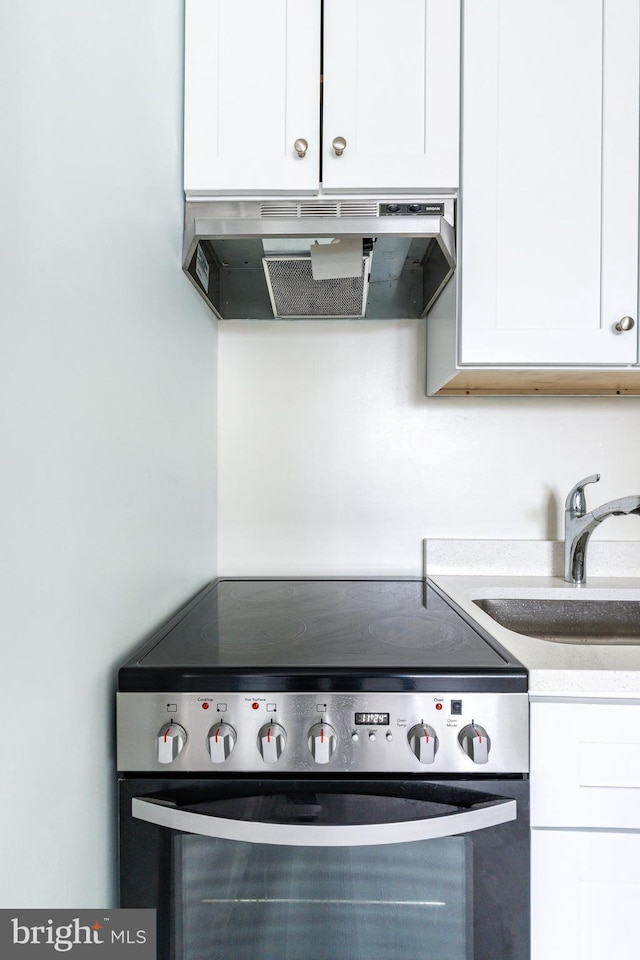 kitchen with sink, stainless steel range with electric cooktop, and white cabinets