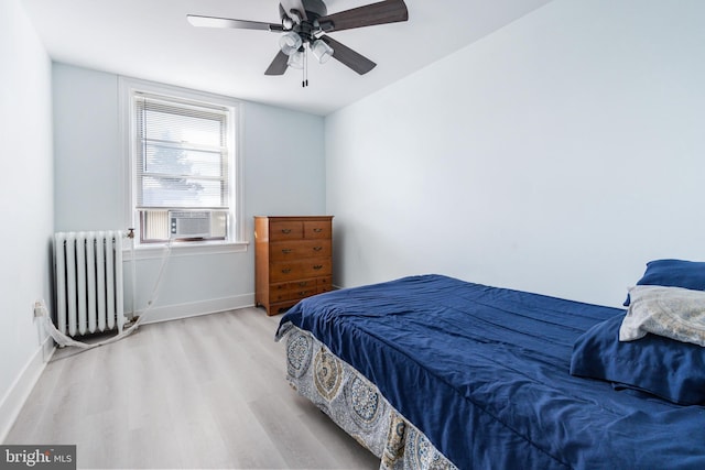 bedroom with cooling unit, ceiling fan, radiator, and light hardwood / wood-style floors