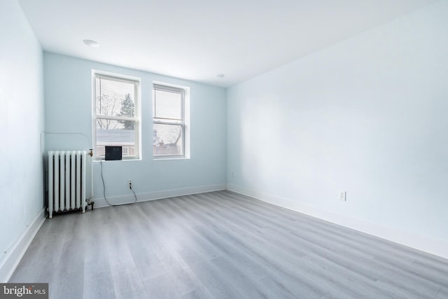 unfurnished room featuring radiator heating unit and light hardwood / wood-style floors