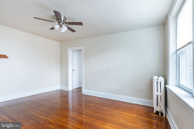 empty room with radiator, dark wood-type flooring, and ceiling fan