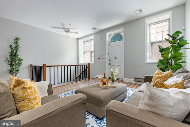 living room featuring ceiling fan, light hardwood / wood-style floors, and a baseboard heating unit