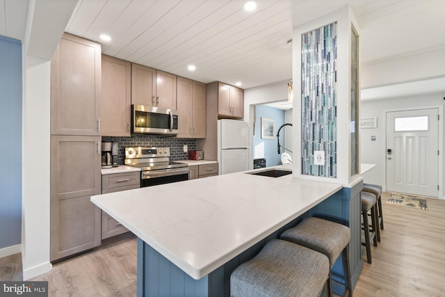 kitchen featuring appliances with stainless steel finishes, sink, a breakfast bar area, decorative backsplash, and a kitchen island with sink