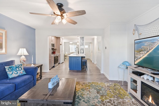 living room with ornamental molding, sink, hardwood / wood-style floors, and ceiling fan