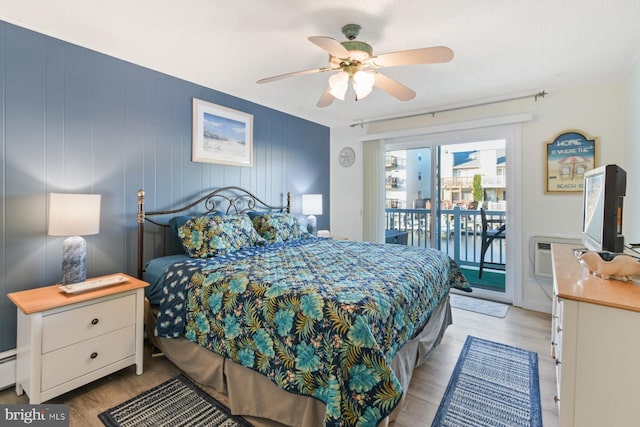 bedroom with ceiling fan, a wall unit AC, access to exterior, and light wood-type flooring