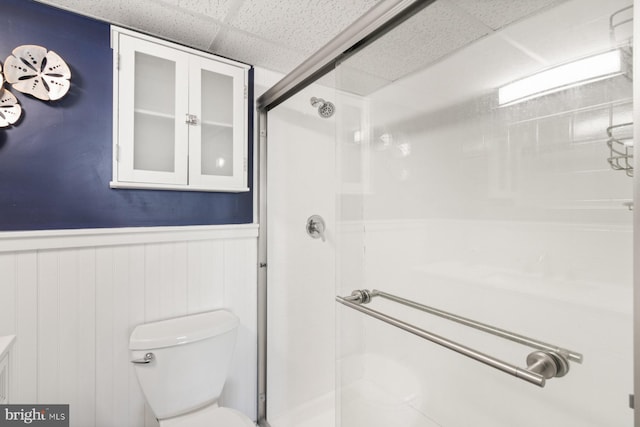 bathroom featuring a paneled ceiling, toilet, and a shower with shower door