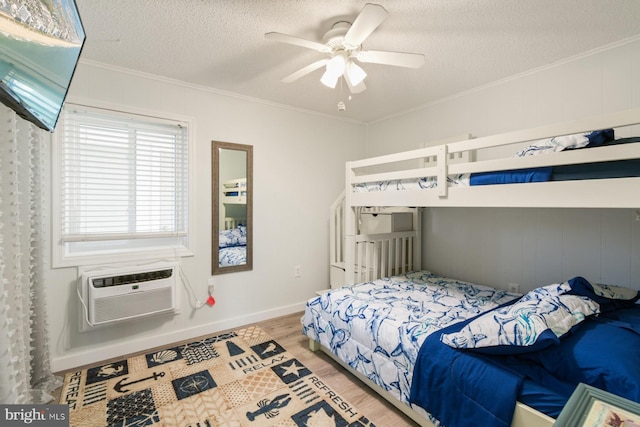 bedroom with crown molding, a textured ceiling, a wall unit AC, and light wood-type flooring