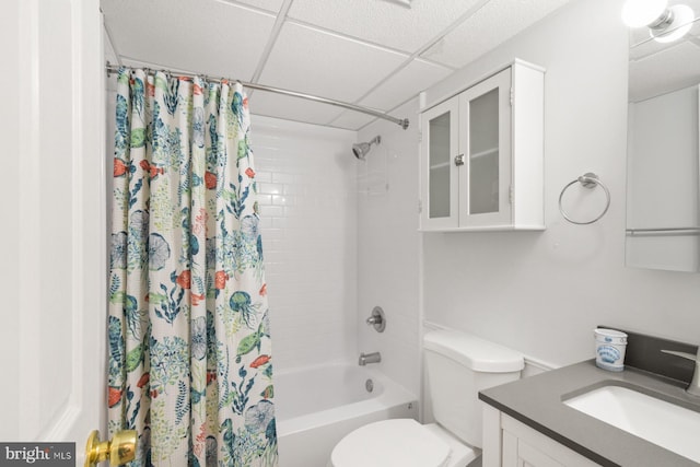 full bathroom with vanity, a drop ceiling, shower / tub combo with curtain, and toilet