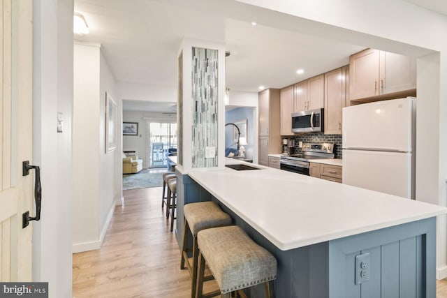 kitchen featuring light brown cabinetry, a breakfast bar, sink, appliances with stainless steel finishes, and decorative backsplash