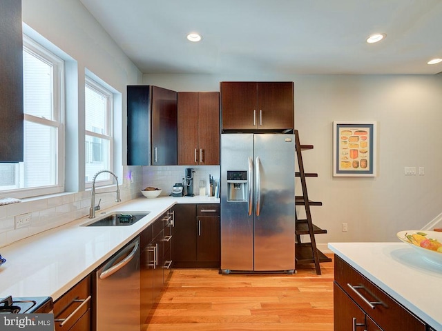 kitchen with tasteful backsplash, sink, light wood-type flooring, stainless steel appliances, and dark brown cabinets