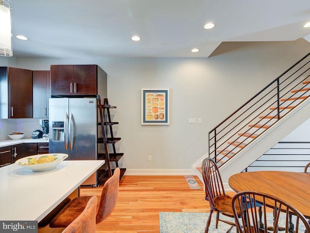 kitchen featuring stainless steel fridge with ice dispenser, backsplash, light hardwood / wood-style flooring, and dark brown cabinets