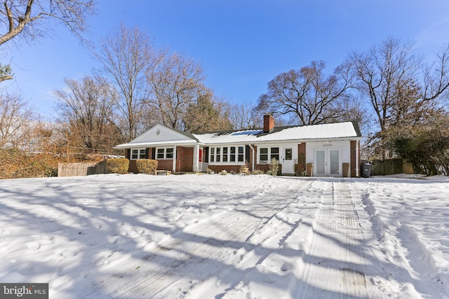 snow covered rear of property with french doors