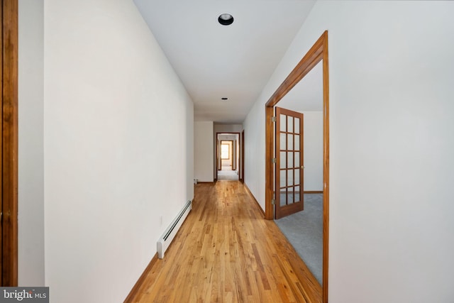 corridor featuring baseboard heating and light wood-type flooring