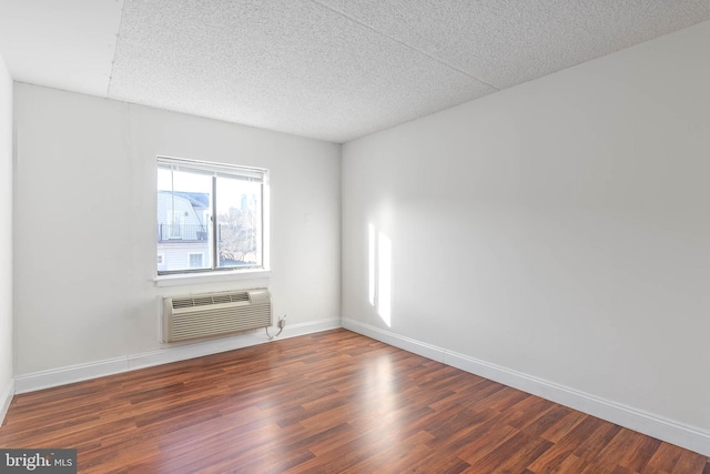 unfurnished room featuring a textured ceiling, dark hardwood / wood-style floors, and a wall mounted air conditioner