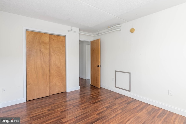 unfurnished bedroom with a closet, dark hardwood / wood-style flooring, and a textured ceiling