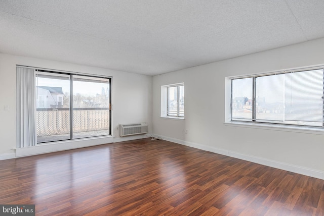 unfurnished room with dark hardwood / wood-style floors, a wall unit AC, and a healthy amount of sunlight