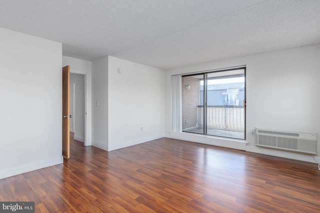 empty room featuring a textured ceiling, dark hardwood / wood-style floors, and a wall mounted air conditioner