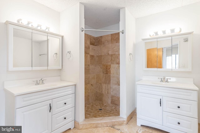 bathroom with vanity, tiled shower, and a textured ceiling