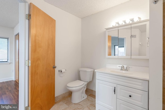 bathroom with a textured ceiling, toilet, and vanity