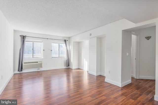 spare room featuring a textured ceiling, dark hardwood / wood-style flooring, and an AC wall unit