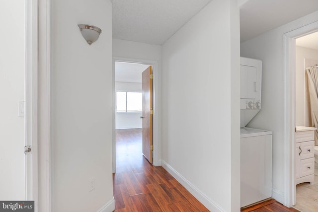 hall featuring stacked washer / dryer and hardwood / wood-style flooring