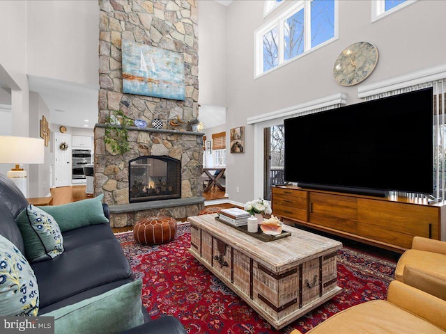 living room with hardwood / wood-style flooring, a fireplace, and a high ceiling