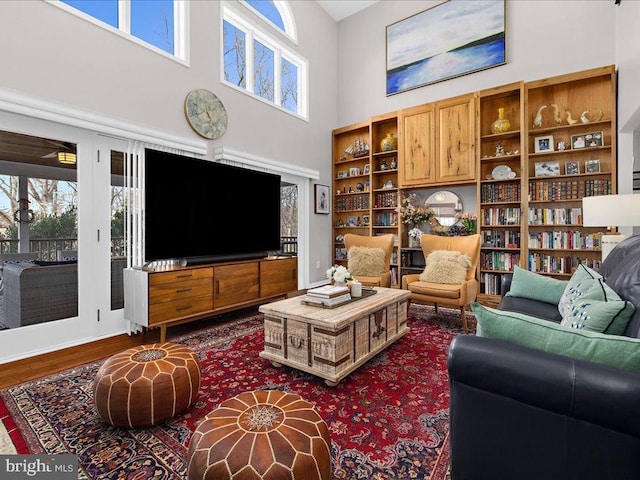 living room with hardwood / wood-style flooring, plenty of natural light, and a high ceiling