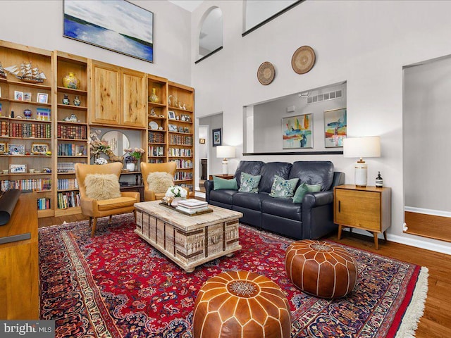 living room with a high ceiling and wood-type flooring