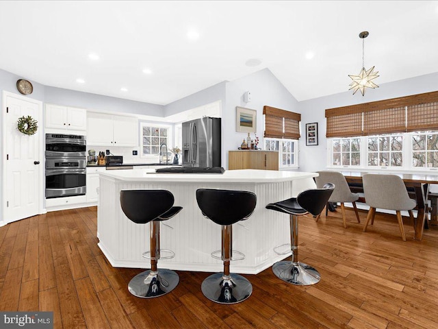 kitchen featuring stainless steel appliances, dark hardwood / wood-style floors, a center island, and white cabinets