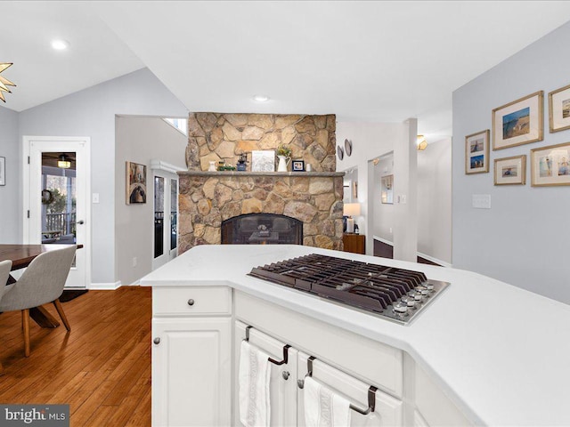 kitchen with light wood-type flooring, lofted ceiling, stainless steel gas cooktop, and white cabinets