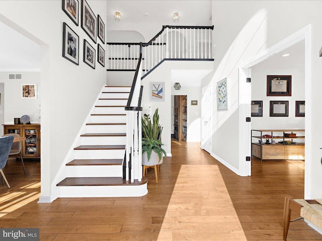 foyer with hardwood / wood-style flooring and a towering ceiling