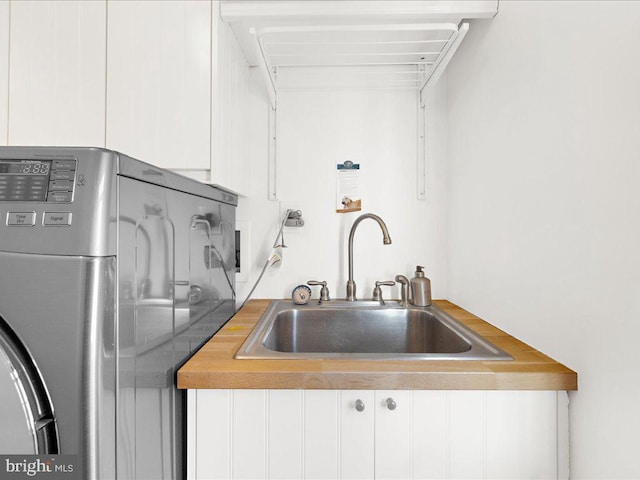 kitchen featuring washer / clothes dryer, white cabinetry, and sink