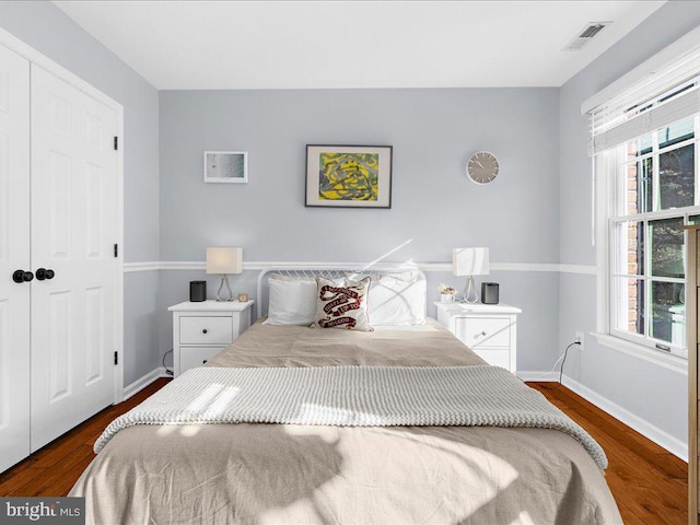 bedroom with dark wood-type flooring, a closet, and multiple windows