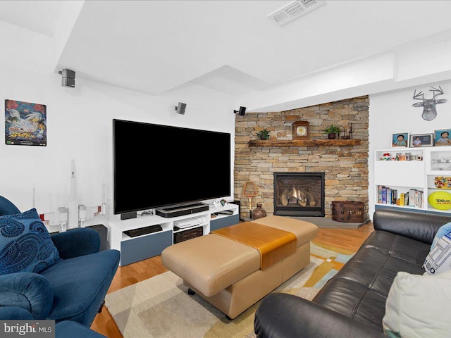 living room with a stone fireplace and light wood-type flooring