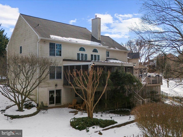 snow covered rear of property with a wooden deck